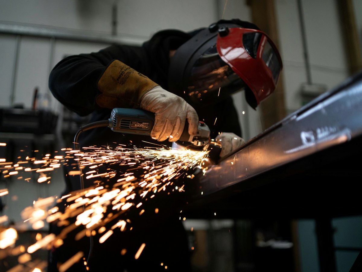Operator grinding a steel section in a fabrication workshop